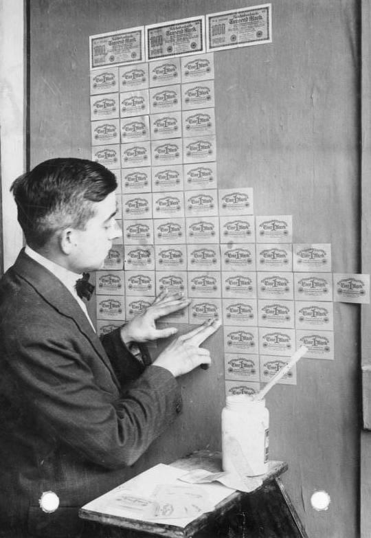 A man papers a wall with worthless German banknotes during the 1923 hyperinflation.