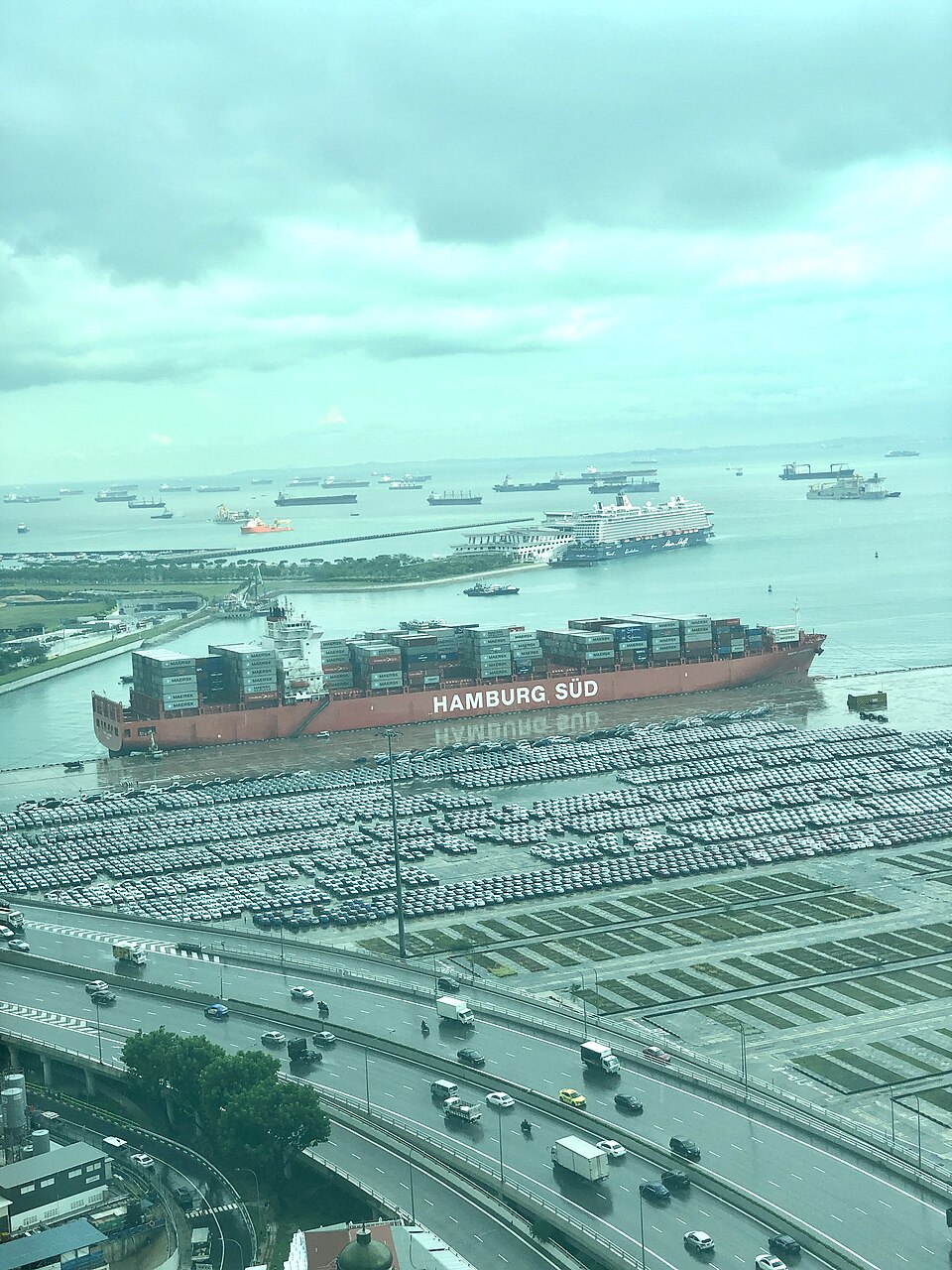 A large container ship in the Port of Singapore, stacked with thousands of shipping containers.